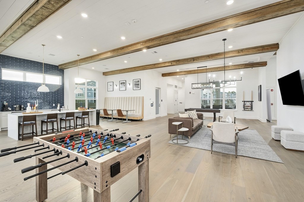 A foosball table is in the middle of a living room at The Waverly at Winter Haven Apartments, Winter Haven, FL, 33884