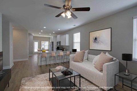 A living room with a couch, a coffee table, and a ceiling fan.