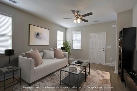 A living room with a couch, a coffee table, and a ceiling fan.