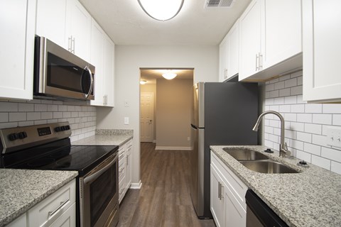A kitchen with white cabinets and black appliances.