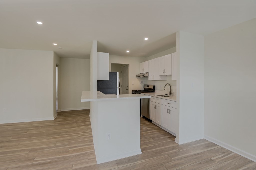 A kitchen with white cabinets and a wooden floor.