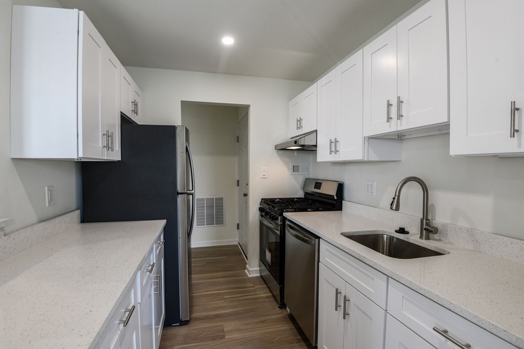 A kitchen with white cabinets and a black refrigerator.