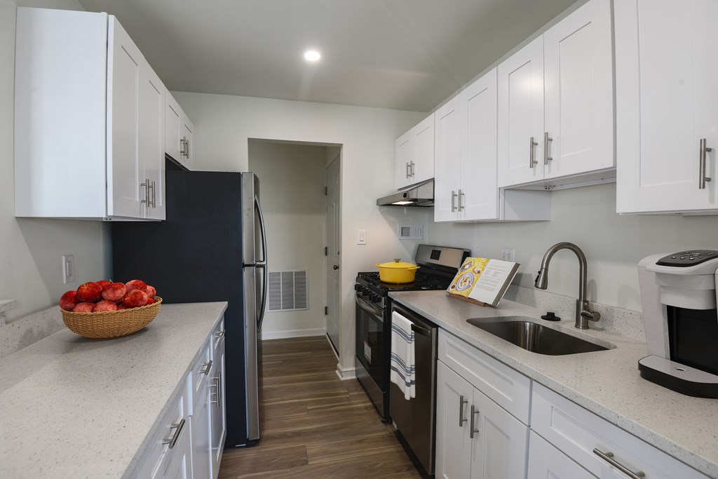 A kitchen with white cabinets and a black refrigerator.