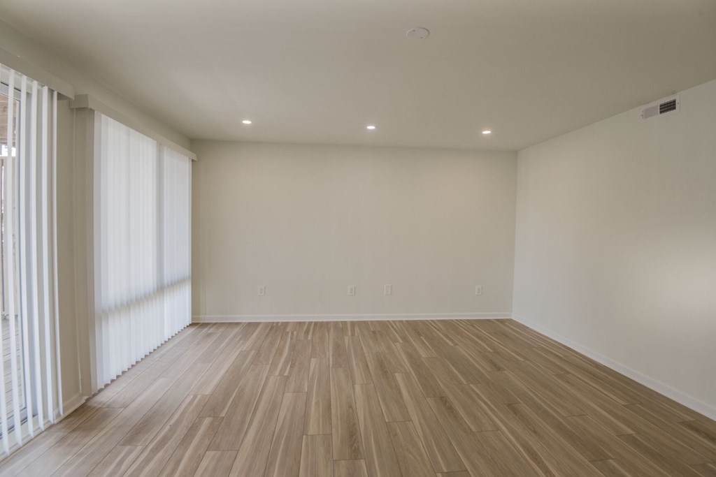 A room with wooden flooring and white walls.