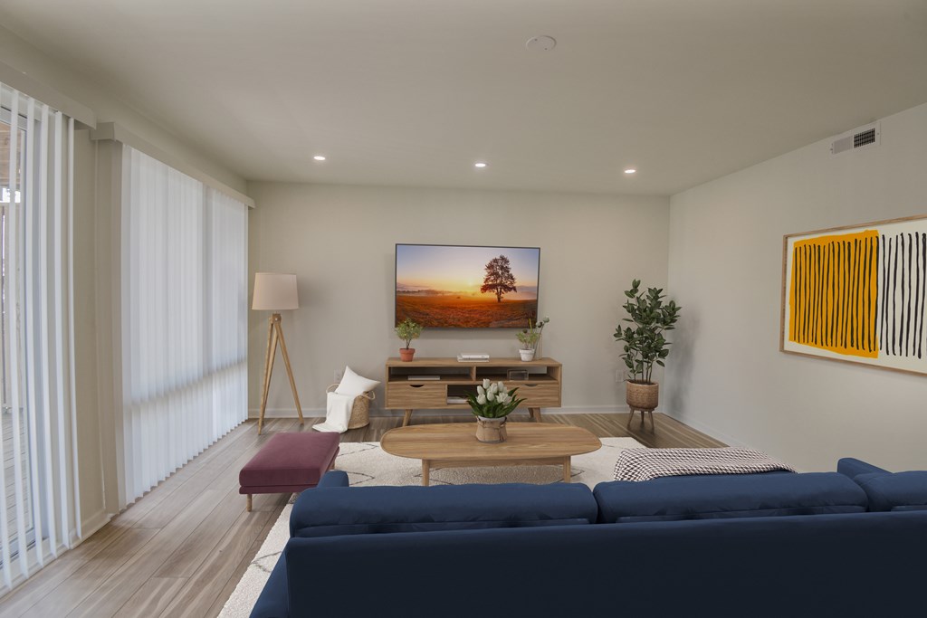 A modern living room with a blue sofa and a flat screen TV mounted on the wall.