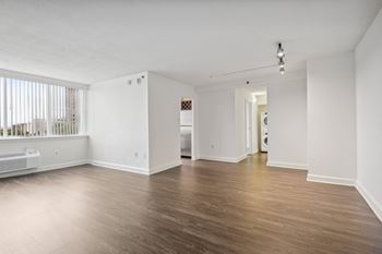 the living room and dining room of an apartment with white walls and wood floors