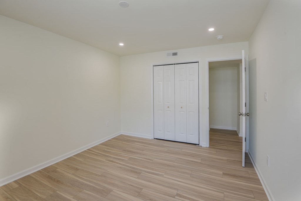 A room with a white door and wooden flooring.