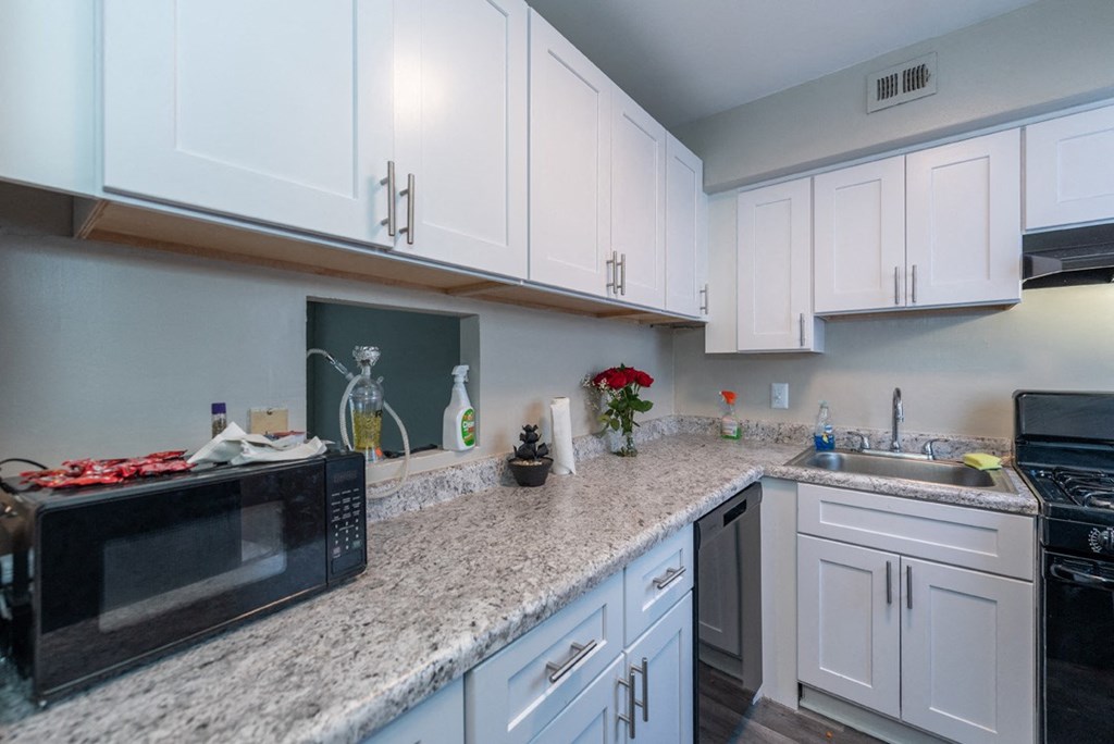 a kitchen with white cabinets and a counter top with a microwave and a sink