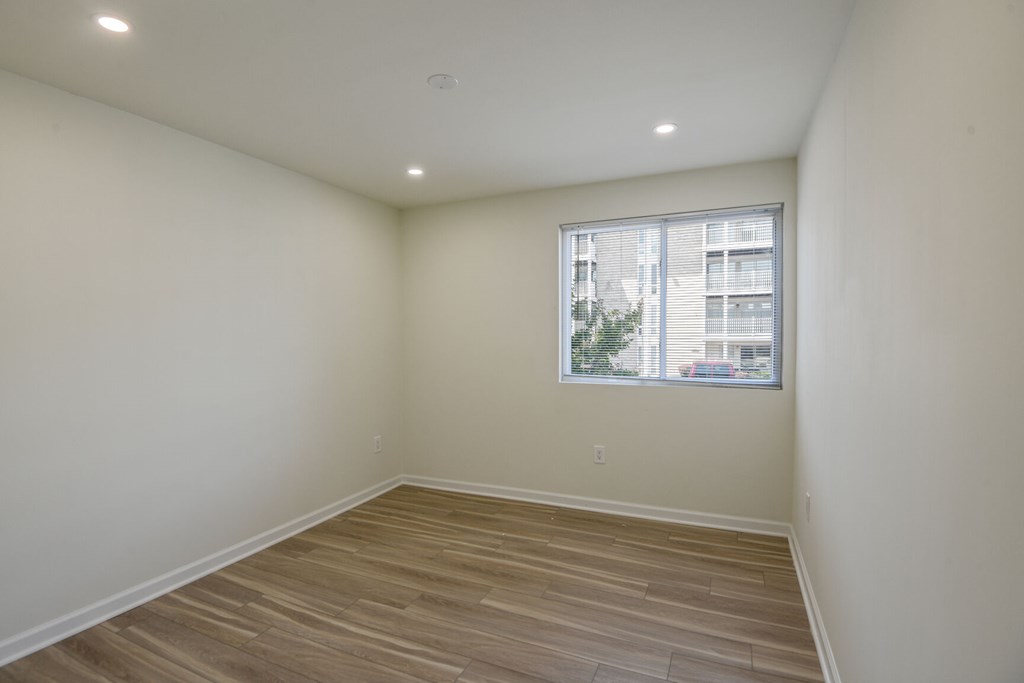 Empty room with wooden flooring and a window.