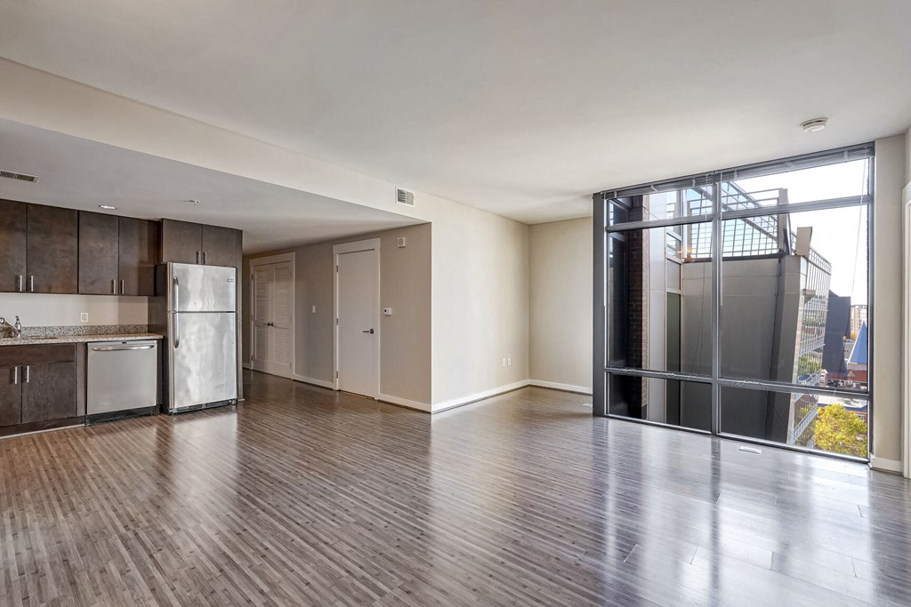 an empty living room with a kitchen and a glass door