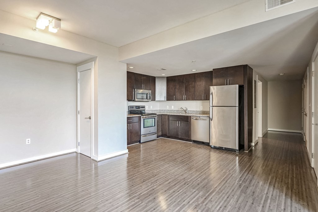 an empty kitchen with stainless steel appliances and wooden floors