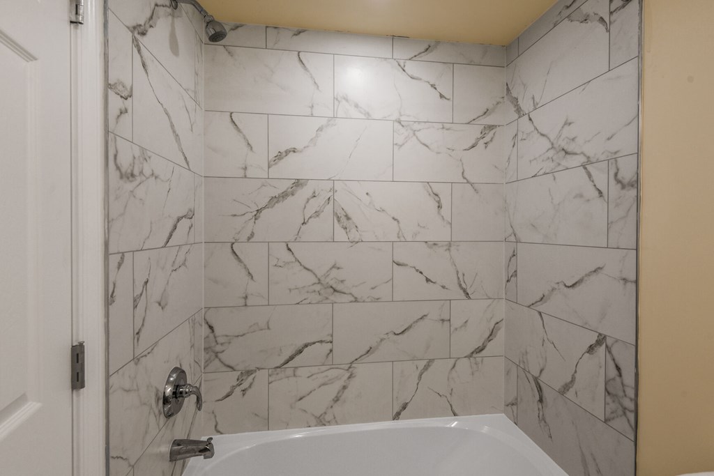 A white bathroom with a marble tile wall.
