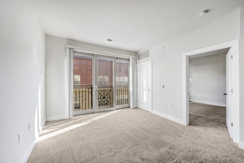 A spacious room with a carpeted floor and a sliding glass door.