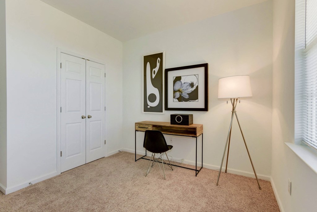 a bedroom with a desk with a lamp and a closet