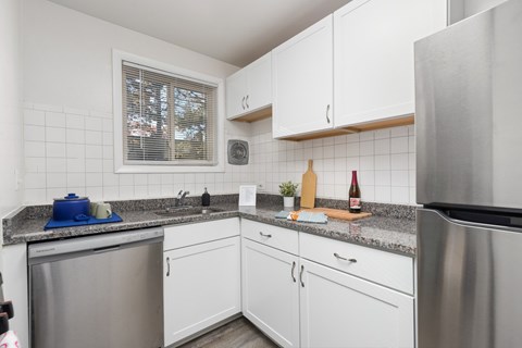 A kitchen with white cabinets and a granite counter top.