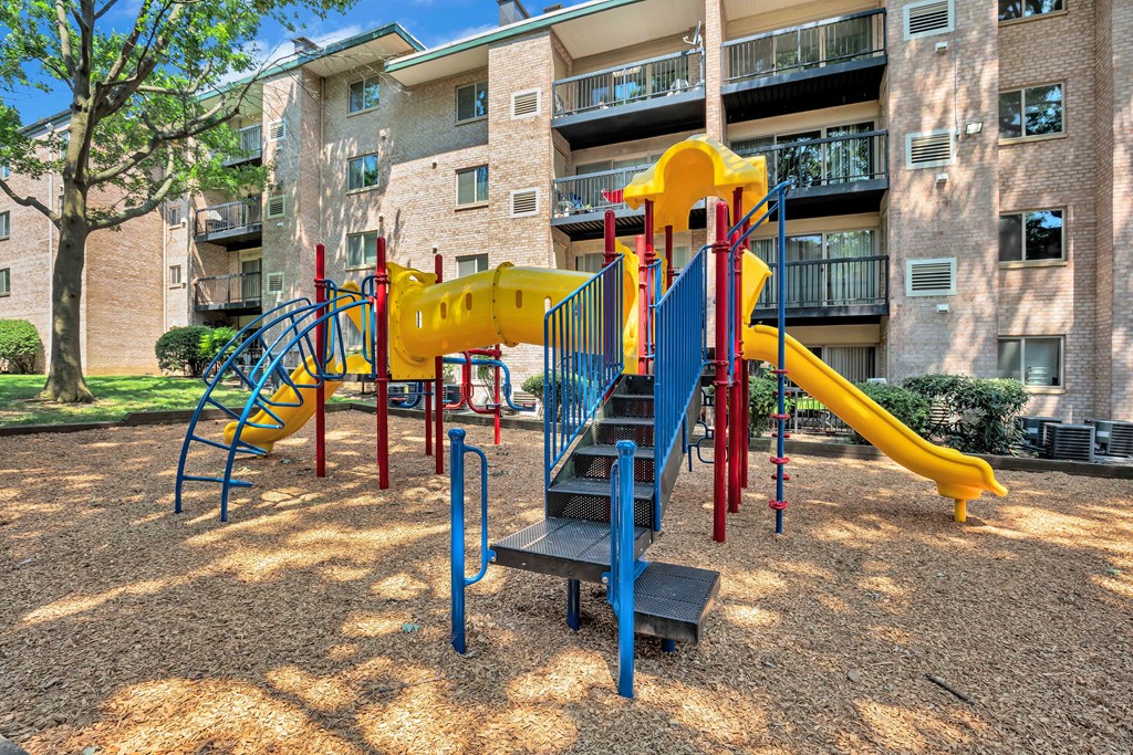 A playground with a yellow slide and a blue slide.