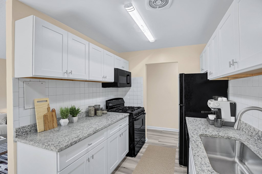 A kitchen with white cabinets and a black refrigerator.