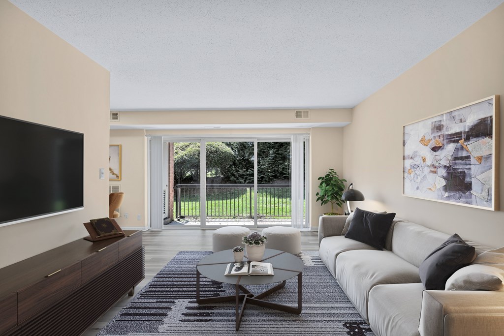 A modern living room with a flat screen TV on the left and a large window with a view of a green lawn outside.