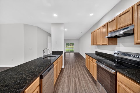 A modern kitchen with wooden cabinets and black countertops.