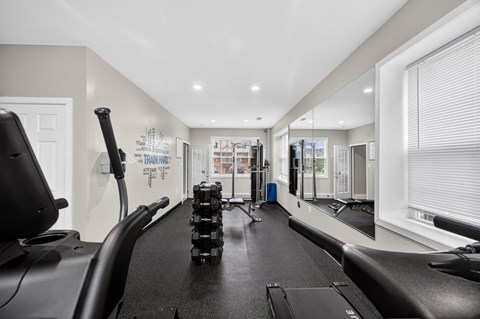 A treadmill is in a spacious gym with a mirrored wall.