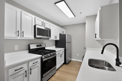 A kitchen with white cabinets and appliances.