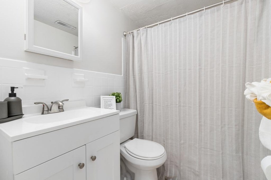 A white bathroom with a toilet, sink, and shower curtain.