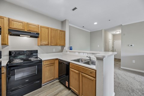 A kitchen with a black stove top oven and wooden cabinets.