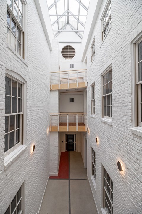 a view of a hallway in a white building with a skylight above it