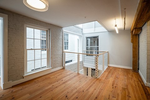 a living room with exposed brick and wood floors and a balcony