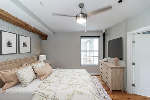 A bedroom with a bed, dresser, and a ceiling fan.