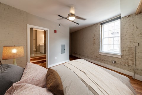 A bedroom with a bed, pillows, a ceiling fan, and a window.