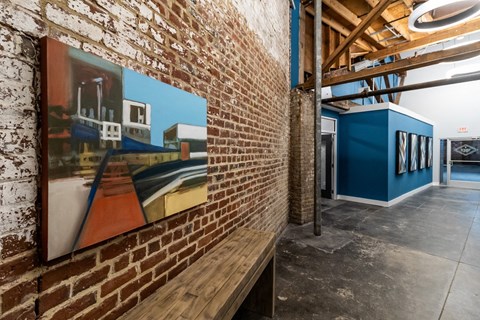 a brick wall with a painting and a wooden bench