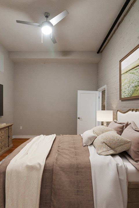 A bedroom with a bed, a ceiling fan, and a painting on the wall.