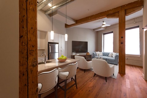 A modern kitchen with white chairs and a wooden floor.