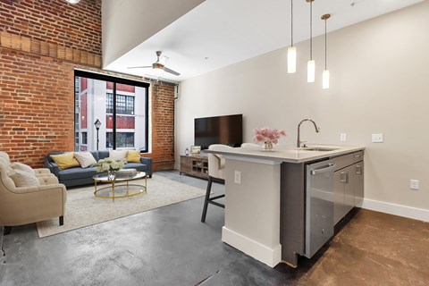 A kitchen with a brick wall and a grey counter.