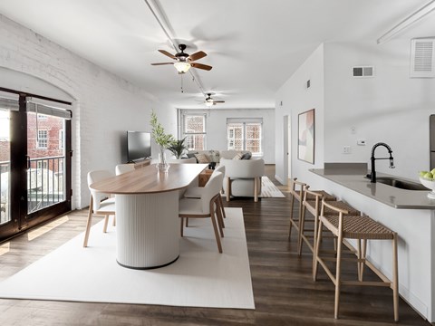 A modern kitchen with a white ceiling fan and wooden floors.