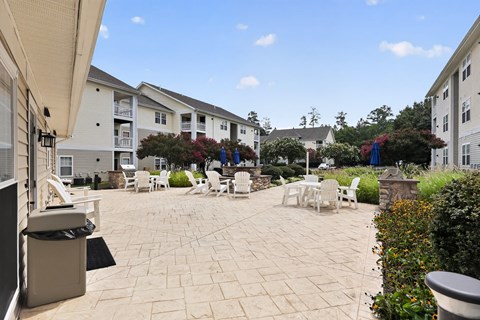 A patio area with tables and chairs surrounded by apartment buildings.