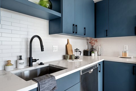 A kitchen with a white sink and a black faucet.