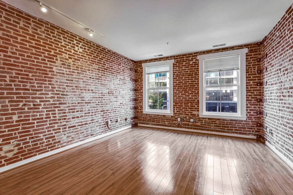 an empty room with a brick wall and wood floors