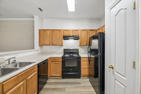 A kitchen with black appliances and wooden cabinets.