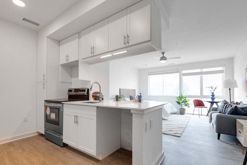 a kitchen with a stove top oven next to a living room