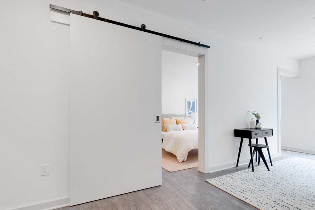 a white bedroom with a white bed and a white desk with a black chair