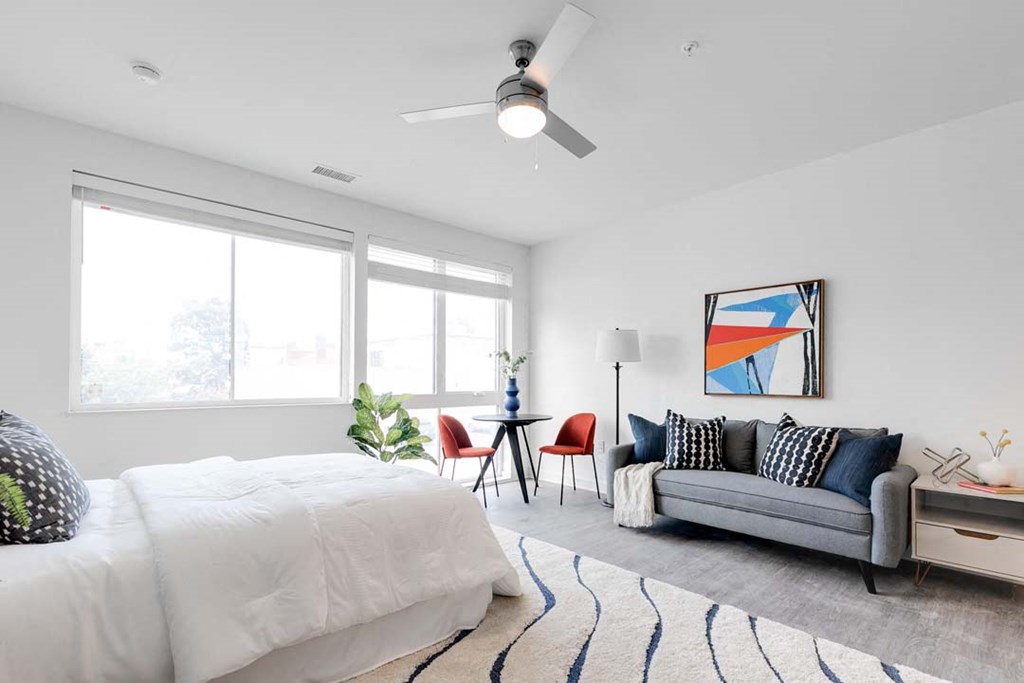 a bedroom with a bed and a couch in front of a window