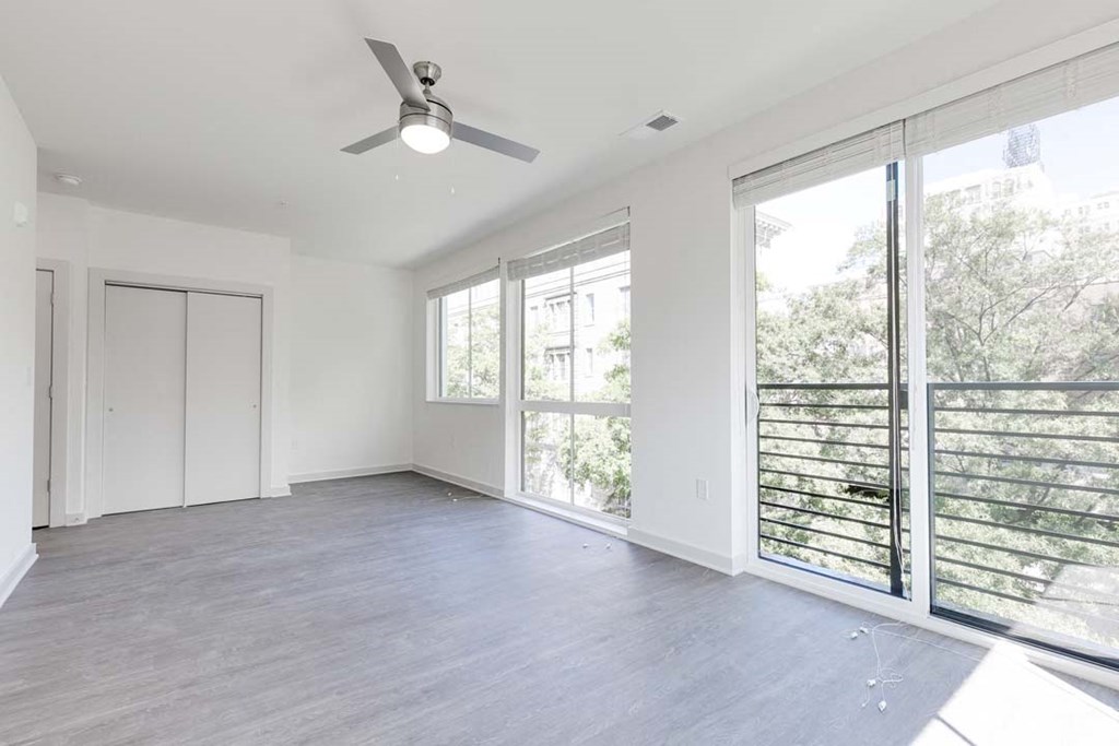 an empty room with a ceiling fan and large windows