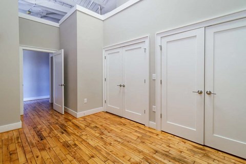a bedroom with three closets and a wood floor