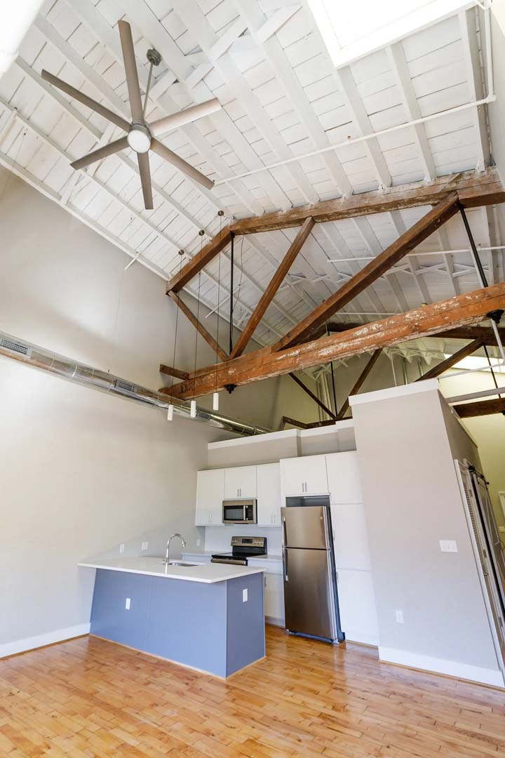 an empty room with a kitchen and a ceiling fan