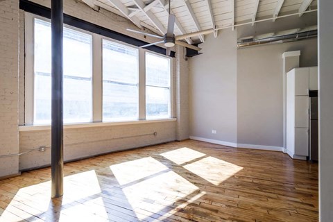 an empty room with large windows and wooden floors