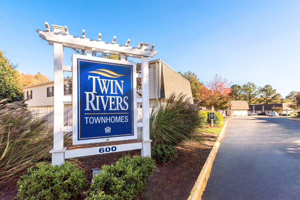 A sign for Twin Rivers Townhomes stands in front of a building.