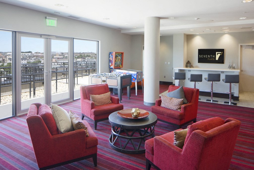 a living room with red chairs and a bar and a balcony