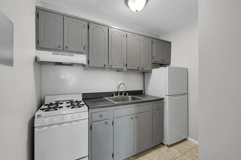 A kitchen with a white stove, sink, and cabinets.